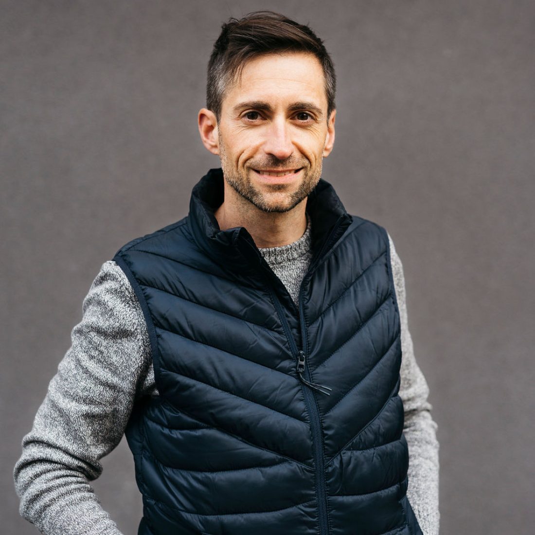Portrait of a man in casual clothes, against a grey background